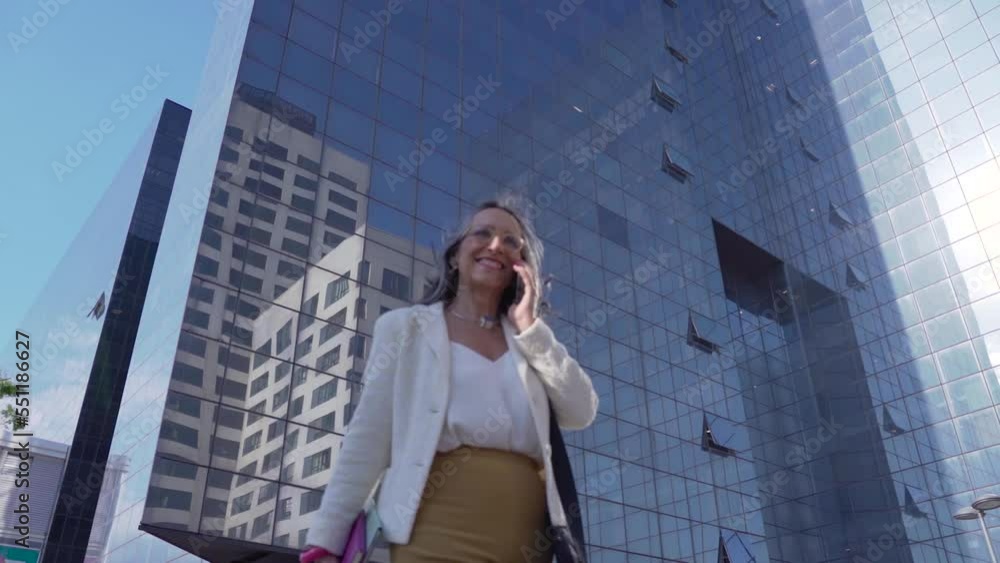 Happy attractive businesswoman talking with her smart phone in front of a modern building. High quality photo Happy attractive businesswoman talking with her smart phone in front of a modern building. High quality photo