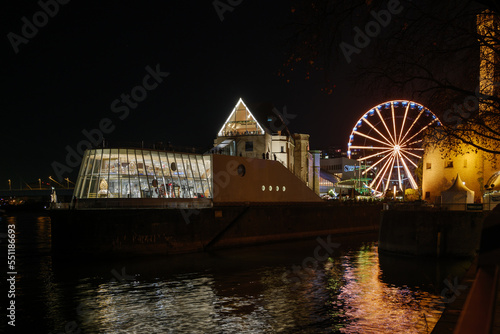 Outdoor night scenery along riverside of Rhine river and background of Hafen Weihnachtsmarkt near Chocolate Museum during Christmas market in winter season. 