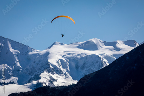 Paragliding above Bernina mountain range with glaciers in the Alps, Switzerland