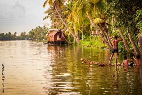 Shallow focus of people on the river surrounded by tropical trees and houseboats as a background photo