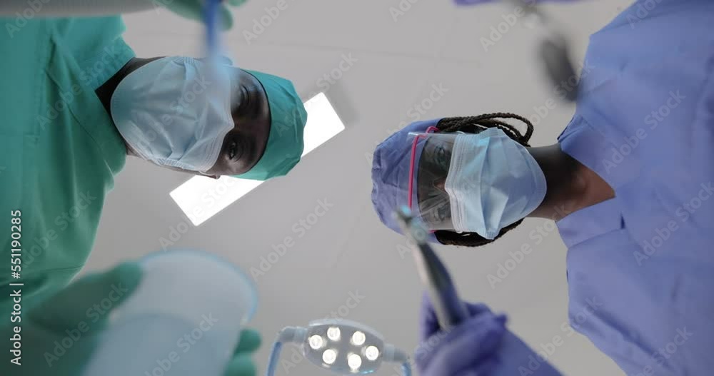 An African dentist and her assistant during a visit, point of view of the client's mouth.