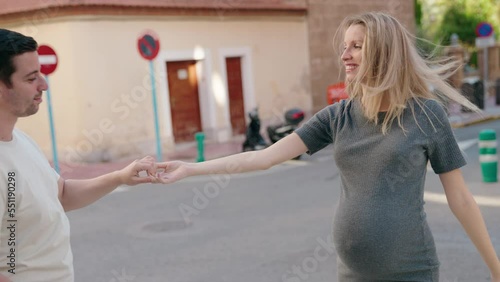 Man and woman couple expecting baby dancing at street