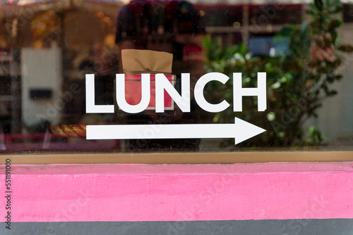 Painted Lunch and arrow symbol sign on a clear glass wall at Miami, Florida