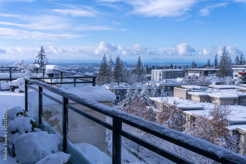 Snowed-in BC rooftop patio with views over residential community of UniverCity Highlands on Burnaby Mountain, BC during early winter.