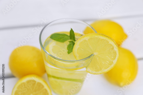 Glass of water with lemons and mint on white wooden table, closeup © New Africa