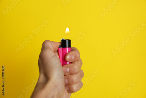 Woman holding pink lighter on yellow background, closeup. Space for text