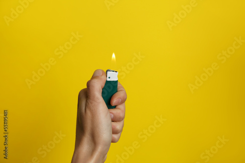 Woman holding green lighter on yellow background, closeup. Space for text