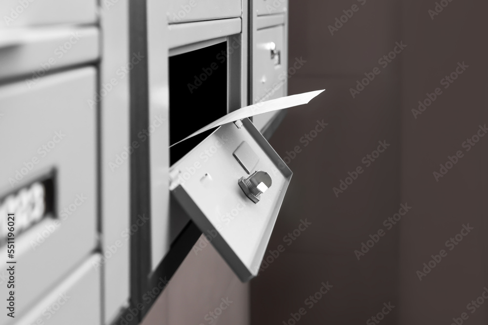 Open metal mailbox with envelope indoors, closeup view
