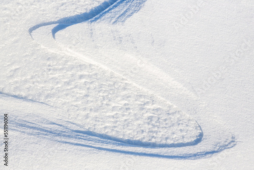 Beautiful winter background with snowy ground. Natural snow texture. Wind sculpted patterns on snow surface. © Andrei Stepanov