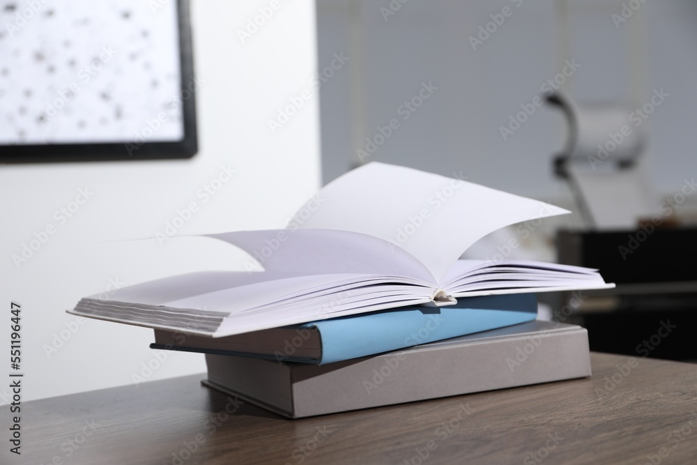 Stack of different hardcover books on wooden table indoors Stack of different hardcover books on wooden table indoors