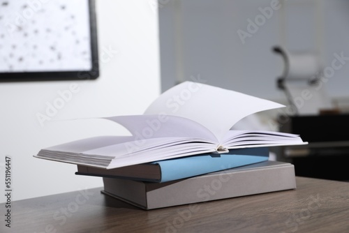 Stack of different hardcover books on wooden table indoors