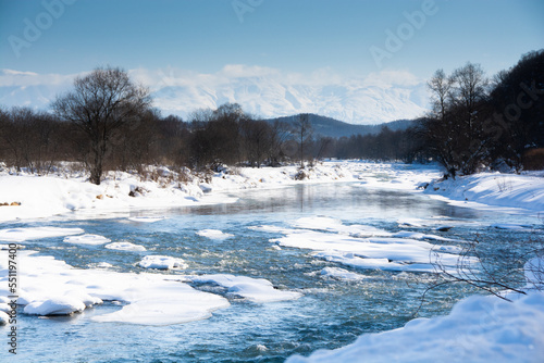 冬の河原と雪山と青空　十勝岳連峰

