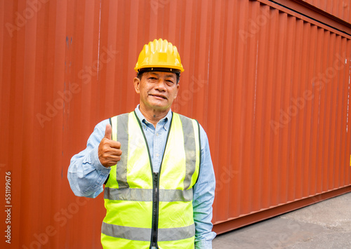 Portrait of confident senior asian engineer thumbs up like gesture with container background