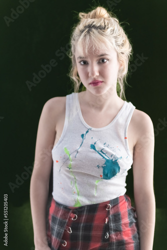 Young LA citizen in designer tank top and short plaid skirt poses in studio in a casual way.