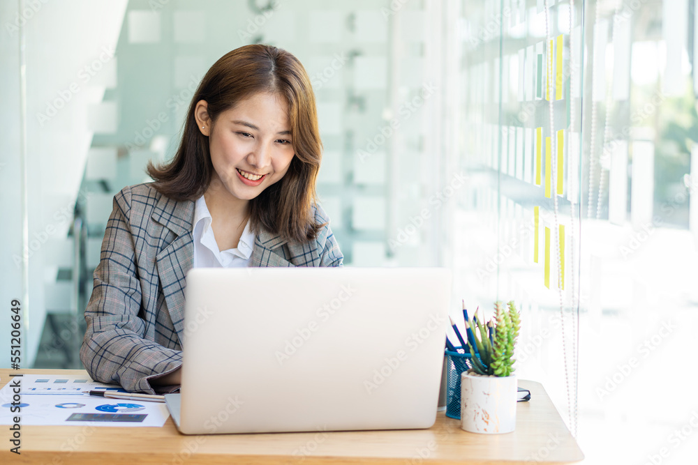 Young successful young asian businesswoman working with smartphone and laptop to contact clients, financial concept Young successful young asian businesswoman working with smartphone and laptop to contact clients, financial concept