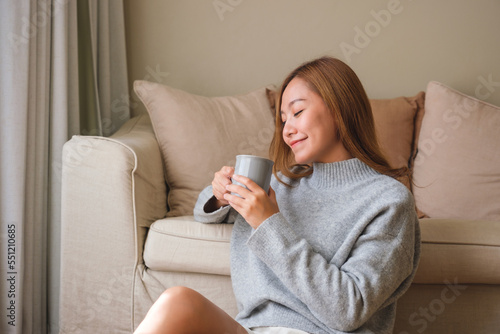 Portrait image of a beautiful young asian woman drinking hot coffee and relaxing at home