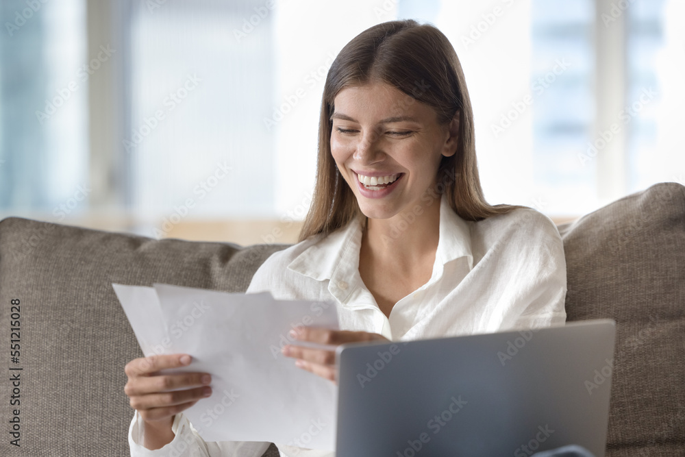 Cheerful young freelance employee woman reading document at laptop, smiling at good news, sales report, job result, agreement deal conditions. Student getting letter with good news Cheerful young freelance employee woman reading document at laptop, smiling at good news, sales report, job result, agreement deal conditions. Student getting letter with good news