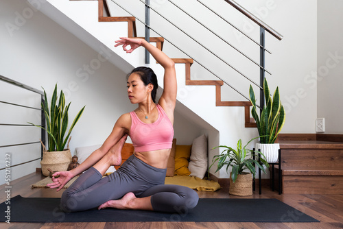Young flexible Asian woman doing beautiful yoga asana at home living room. Healthy lifestyle