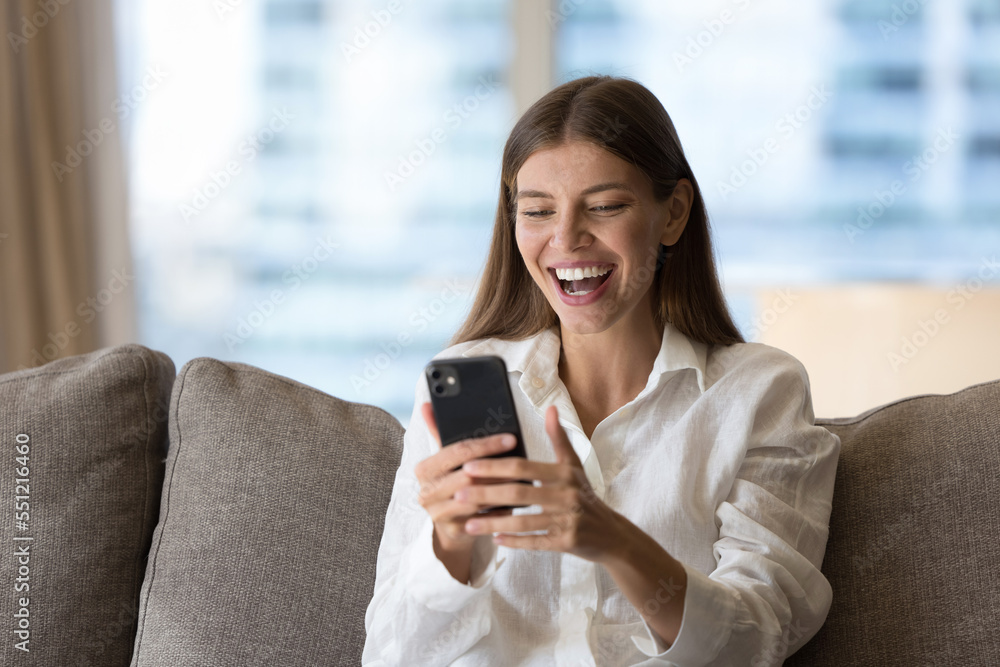 Cheerful cellphone user girl excited with good news, success, win, reading text message on mobile phone, getting good surprising news from video call talk, smiling, laughing, shouting