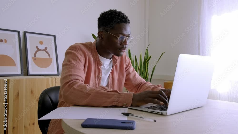 Young African American man typing on laptop, concentrated working from home. 4k video. Young African American man typing on laptop, concentrated working from home. 4k video.
