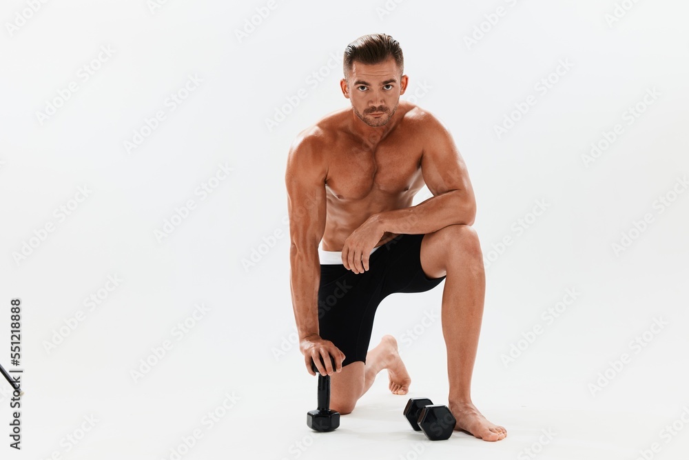 Man athletic body bodybuilder posing with dumbbells with naked torso abs full-length in the background, fitness class. Advertising, sports, active lifestyle, competition, challenge concept. Man athletic body bodybuilder posing with dumbbells with naked torso abs full-length in the background, fitness class. Advertising, sports, active lifestyle, competition, challenge concept.