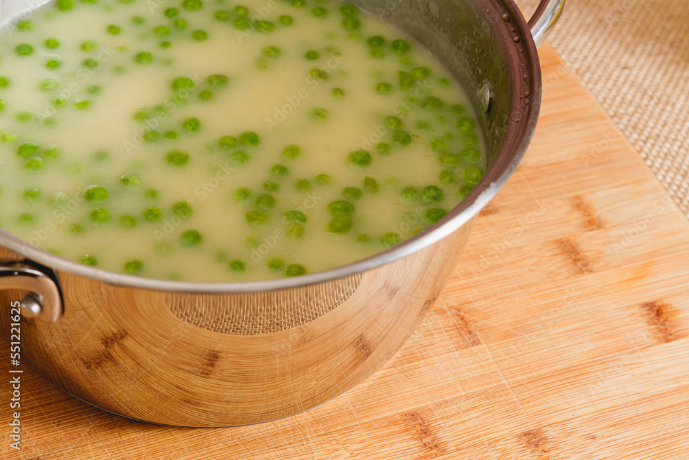 Creamy celery soup puree with green pea in a cooking pan close-up on rustic background Creamy celery soup puree with green pea in a cooking pan close-up on rustic background