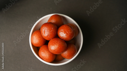 Sweet Gulab Jamun served in white bowl, Famous Indian dessert sweets isolated over black indoor studio background photo