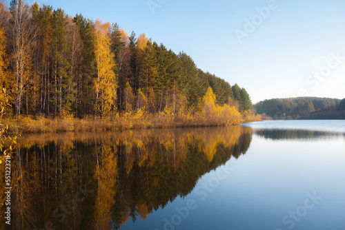Colorful foliage tree reflections in calm pond water on a beautiful autumn day. A quiet and beautiful place to relax. © Анатолий Савицкий