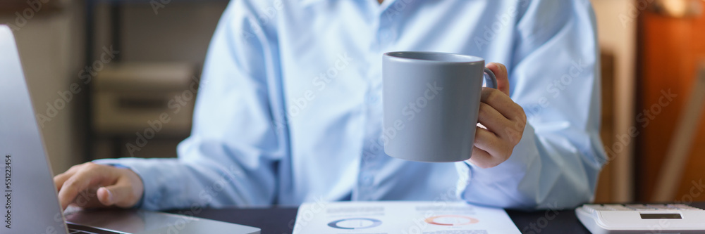 Business concept, Businesswomen is drinking coffee and typing finance data on laptop at workplace Business concept, Businesswomen is drinking coffee and typing finance data on laptop at workplace