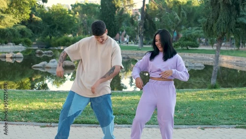 Two young latin friends dancing and smiling at street in a park.