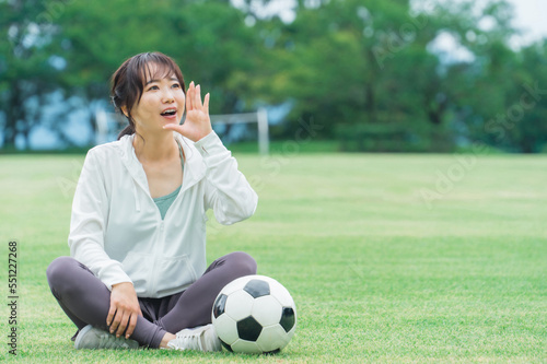 スポーツウェアでサッカーを応援するアジア人女性 