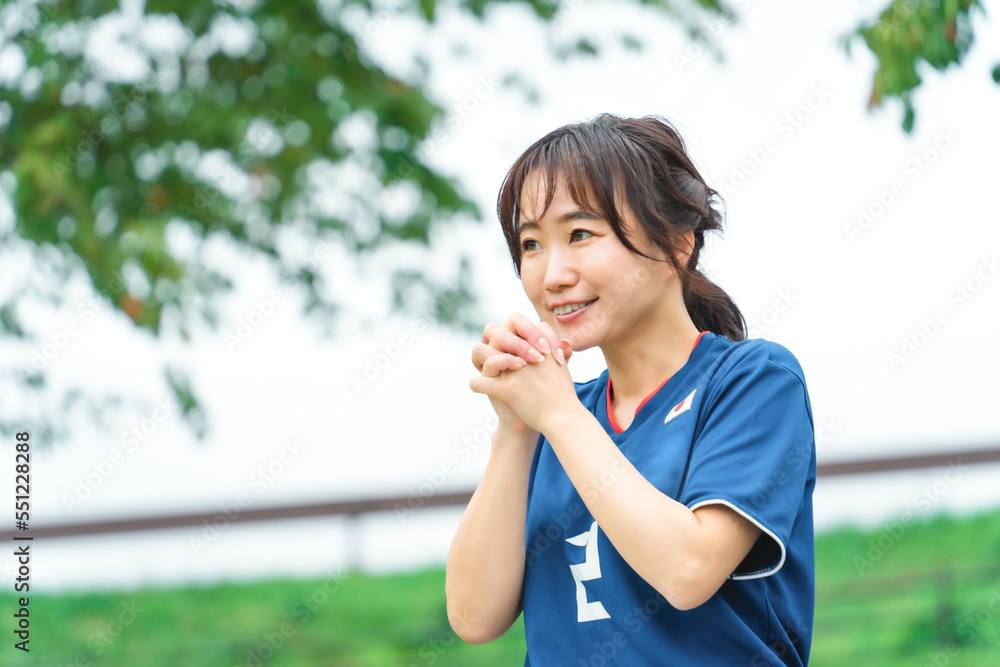 祈るように日本代表を応援するサッカーファン・サポーターの日本人女性
