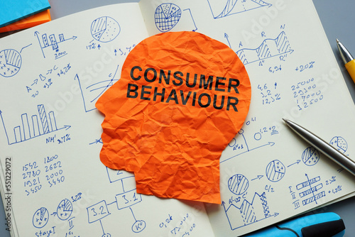 Consumer behaviour sign on a paper head and open notepad with marks. photo