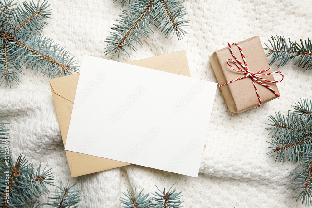 Christmas greeting card mockup with gift box and fir tree branches on white knitted pullover background, top view, flat lay Christmas greeting card mockup with gift box and fir tree branches on white knitted pullover background, top view, flat lay