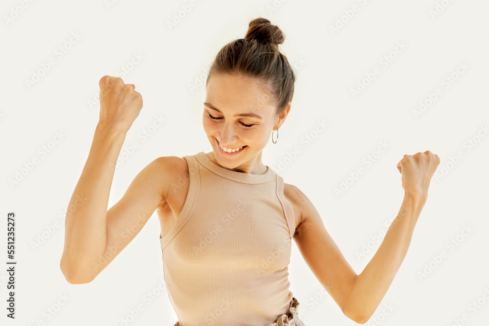 Studio portrait of cute young lady of 20s dancing with triumph, celebrating her success, victory, student girl happy with the end of academic year, clenched fists with closed eyes, isolated on white Studio portrait of cute young lady of 20s dancing with triumph, celebrating her success, victory, student girl happy with the end of academic year, clenched fists with closed eyes, isolated on white