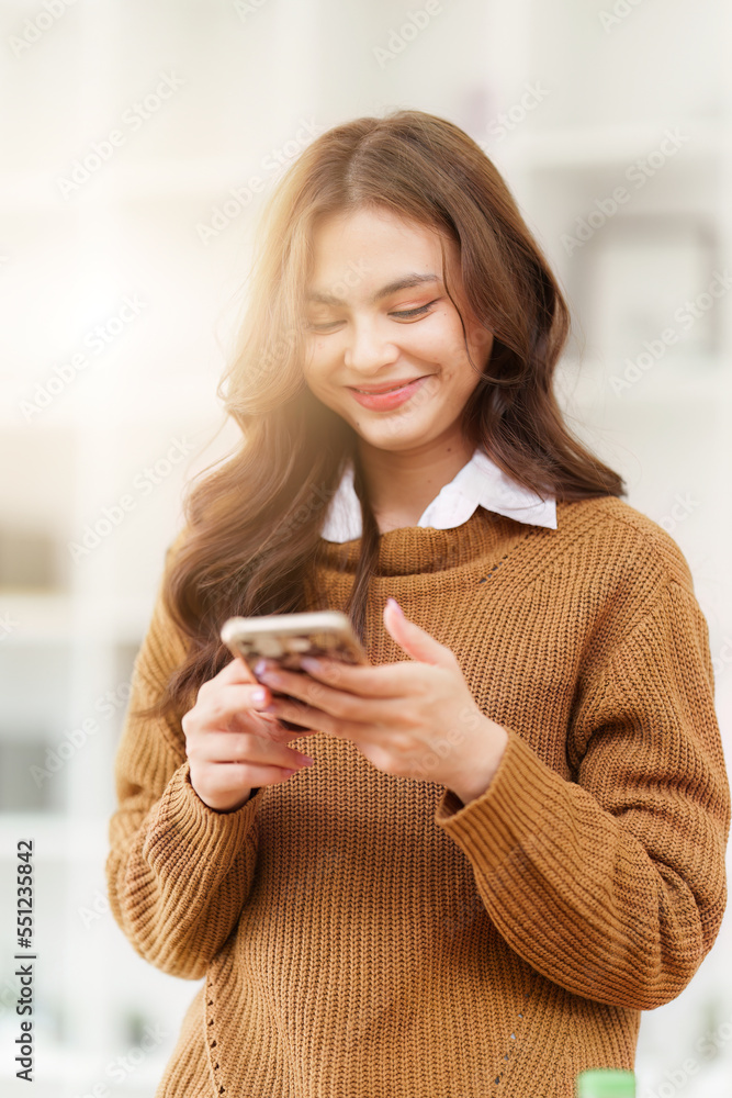 Young Asian Woman using smart phone at home. Female holding cellphone checking email or social media on internet