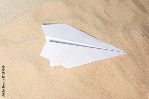 Paper plane on a sandy background, close-up