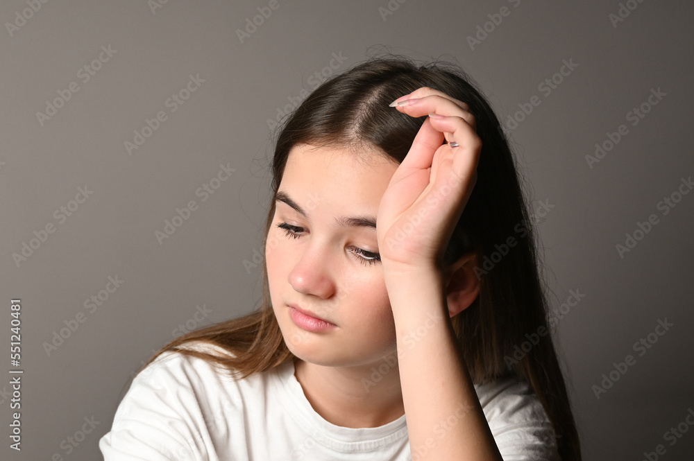 Portrait of sad teen girl on gray background. Teenage girl looking thoughtful about troubles Portrait of sad teen girl on gray background. Teenage girl looking thoughtful about troubles