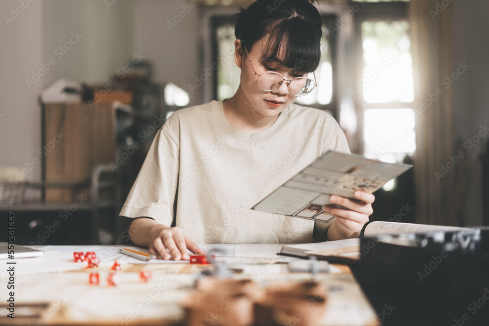 Fototapeta premium Young adult asian woman enjoying role playing tabletop and board game