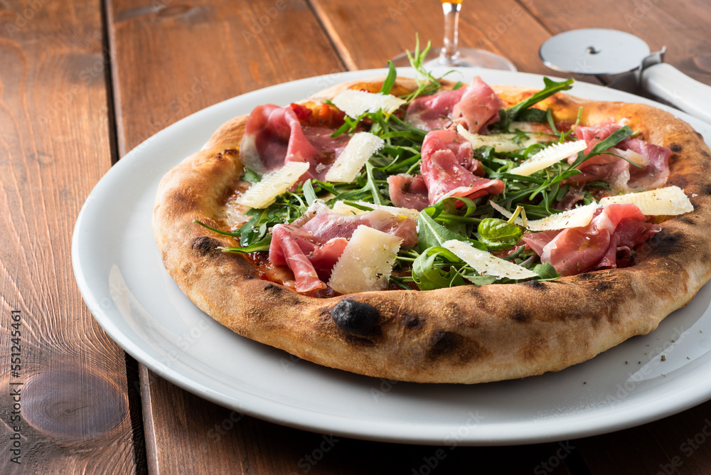 Deliziosa pizza gourmet con prosciutto crudo, scaglie di grana e rucola, cibo italiano Deliziosa pizza gourmet con prosciutto crudo, scaglie di grana e rucola, cibo italiano