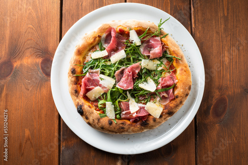 Fotografie Deliziosa pizza gourmet con prosciutto crudo, scaglie di grana e rucola, cibo it