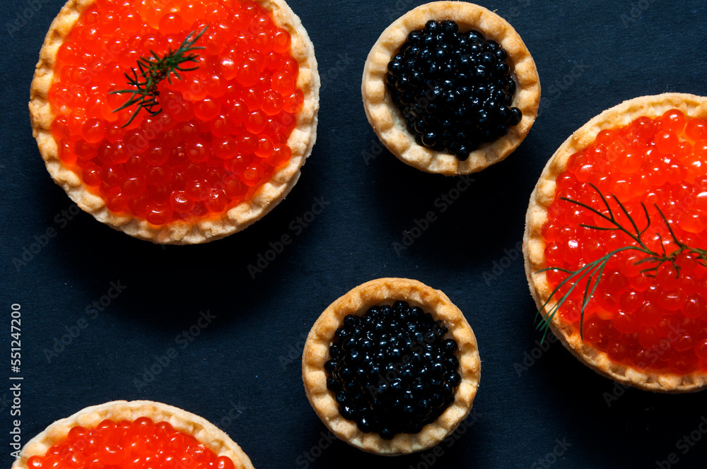 Red and black caviar in tartlets on a black background. Red and black caviar in tartlets on a black background.