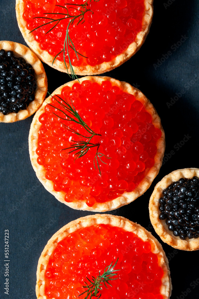 Red and black caviar in tartlets on a black background. Red and black caviar in tartlets on a black background.