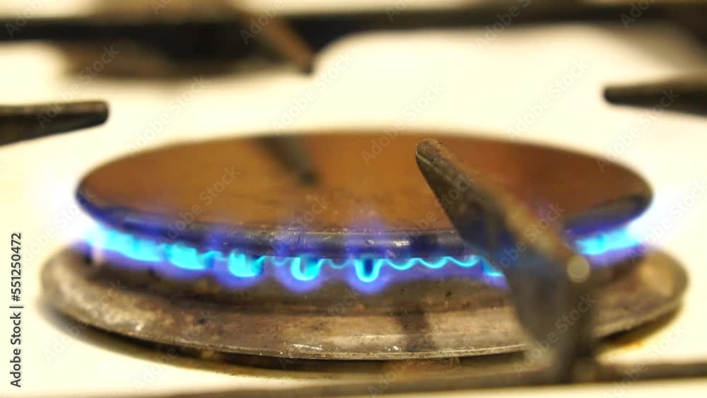 Natural gas burning on white enameled domestic stove at kitchen. Close up of natural gas flames in gas stove on the domestic kitchen. Concept of problems with gas, rising prices. Slow motion. Natural gas burning on white enameled domestic stove at kitchen. Close up of natural gas flames in gas stove on the domestic kitchen. Concept of problems with gas, rising prices. Slow motion.