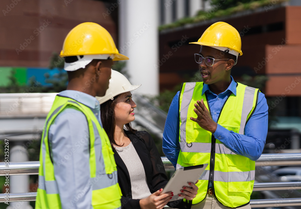 black executive engineer working at construction site outside building in city and talking with caucasian businesswoman and black engineer black executive engineer working at construction site outside building in city and talking with caucasian businesswoman and black engineer