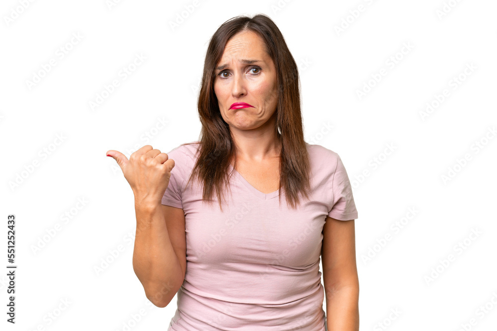 Middle-aged caucasian woman over isolated background unhappy and pointing to the side Middle-aged caucasian woman over isolated background unhappy and pointing to the side