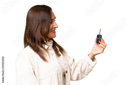 Middle-aged woman holding car keys over isolated background with happy expression