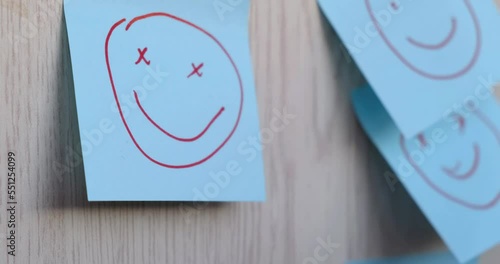 A blue sticker with a funny face drawn with a felt-tip pen is glued to the wall. The concept of happiness, good mood, psychology, luck