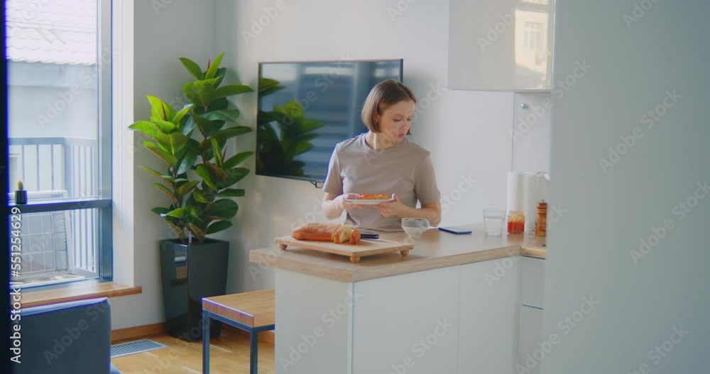 Woman eating sandwich with fruit jam for breakfast drinking coffee in the kitchen at home Woman eating sandwich with fruit jam for breakfast drinking coffee in the kitchen at home