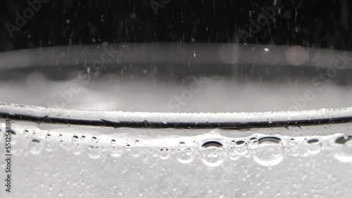 A glass of sparkling water on a black background. Bubbles come out of the glass. Pure mineralized water with gas.